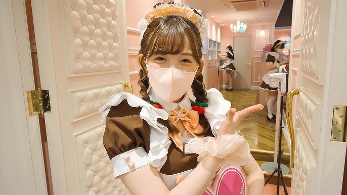 Jovem japonesa com fantasia fofa de maid convida para entrar num maid café em Akihabara, Japão